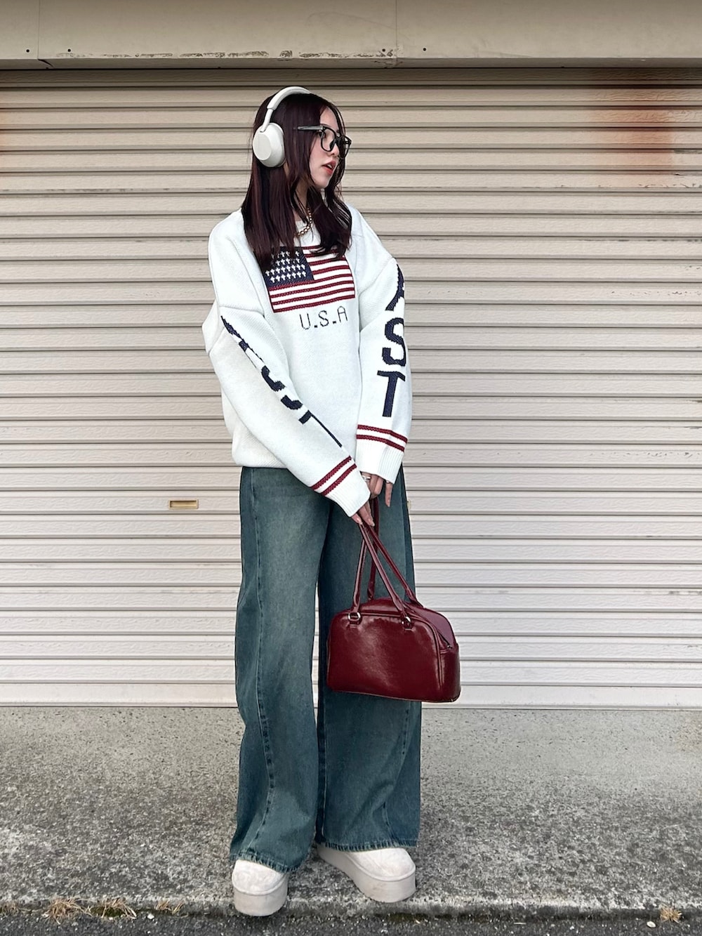 ブルー系のデニムパンツ、ホワイト系のニット/セーター、レッド系のハンドバッグを着用したレディースの冬コーディネートの2枚目の写真