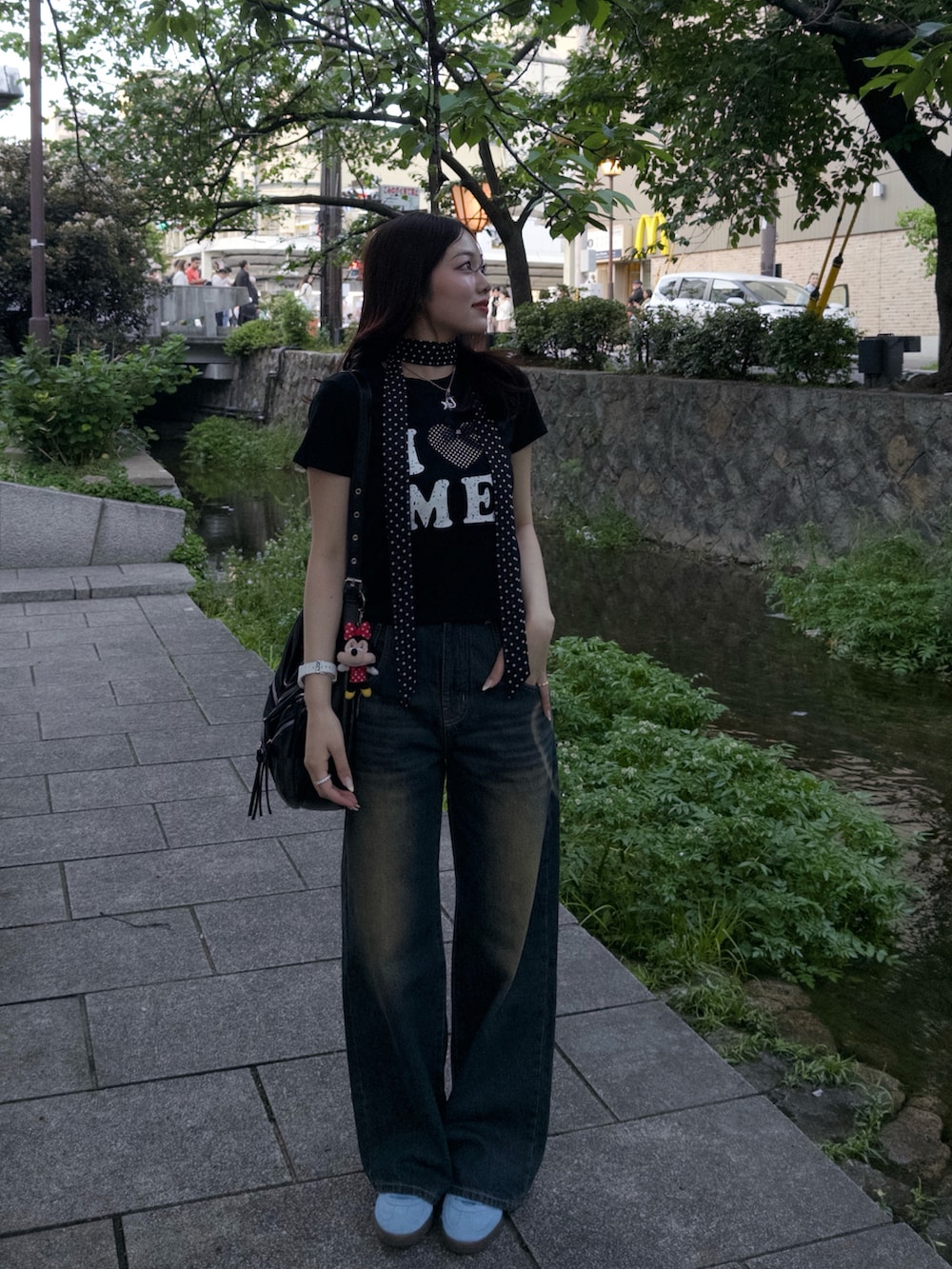 ブラック系のTシャツ/カットソー、ブラック系のショルダーバッグ、ブルー系のデニムパンツを着用したレディースの春コーディネートの3枚目の写真