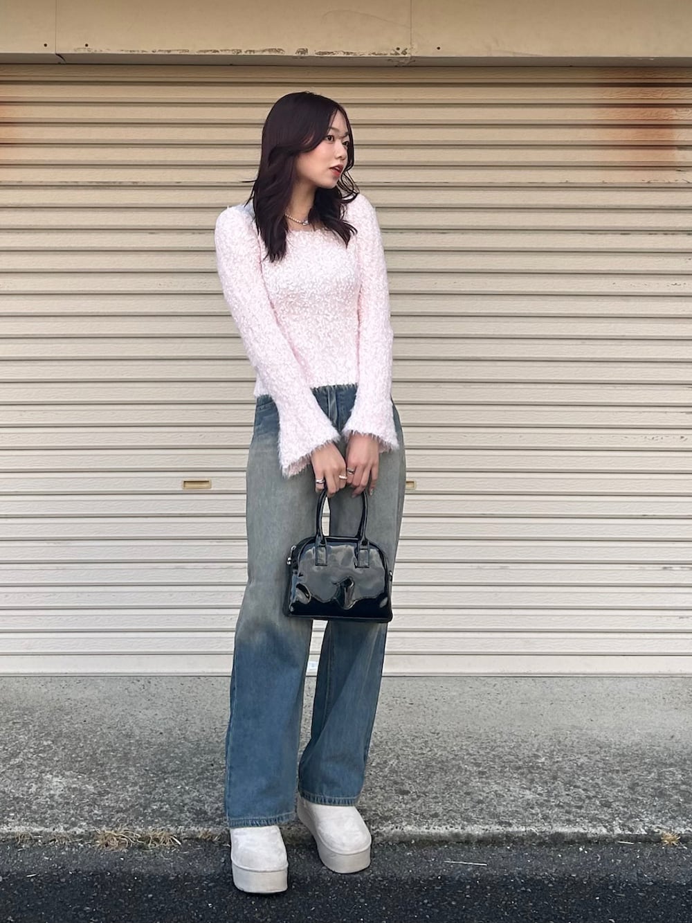 ブラック系のボストンバッグ、ブルー系のデニムパンツ、ブラウン系のブーツを着用したレディースの冬コーディネートの2枚目の写真