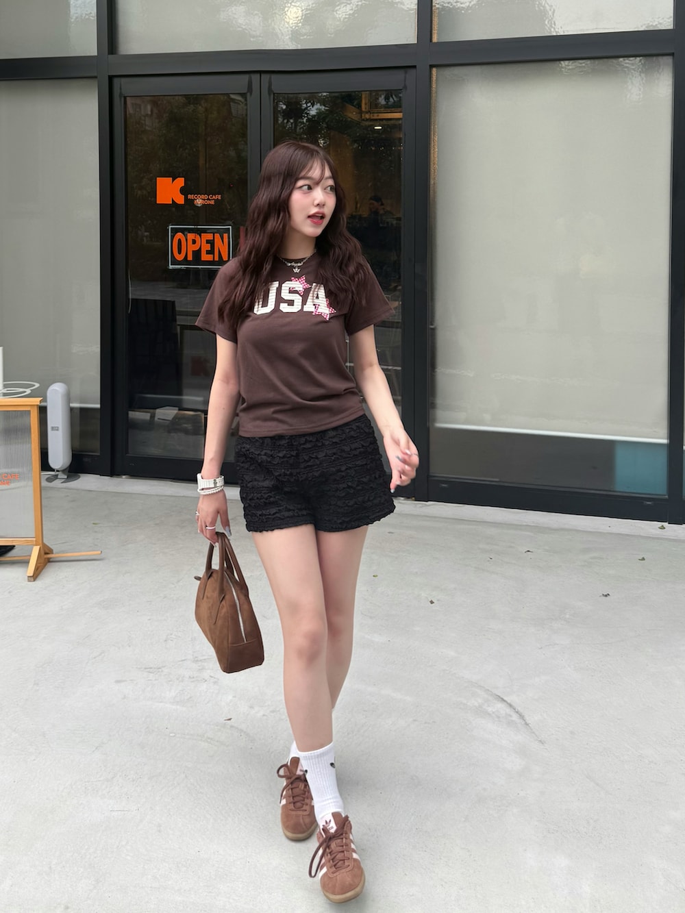 ブラウン系のTシャツ/カットソー、ブラウン系のハンドバッグ、ブラック系のスウェットパンツを着用したレディースの夏コーディネートの2枚目の写真