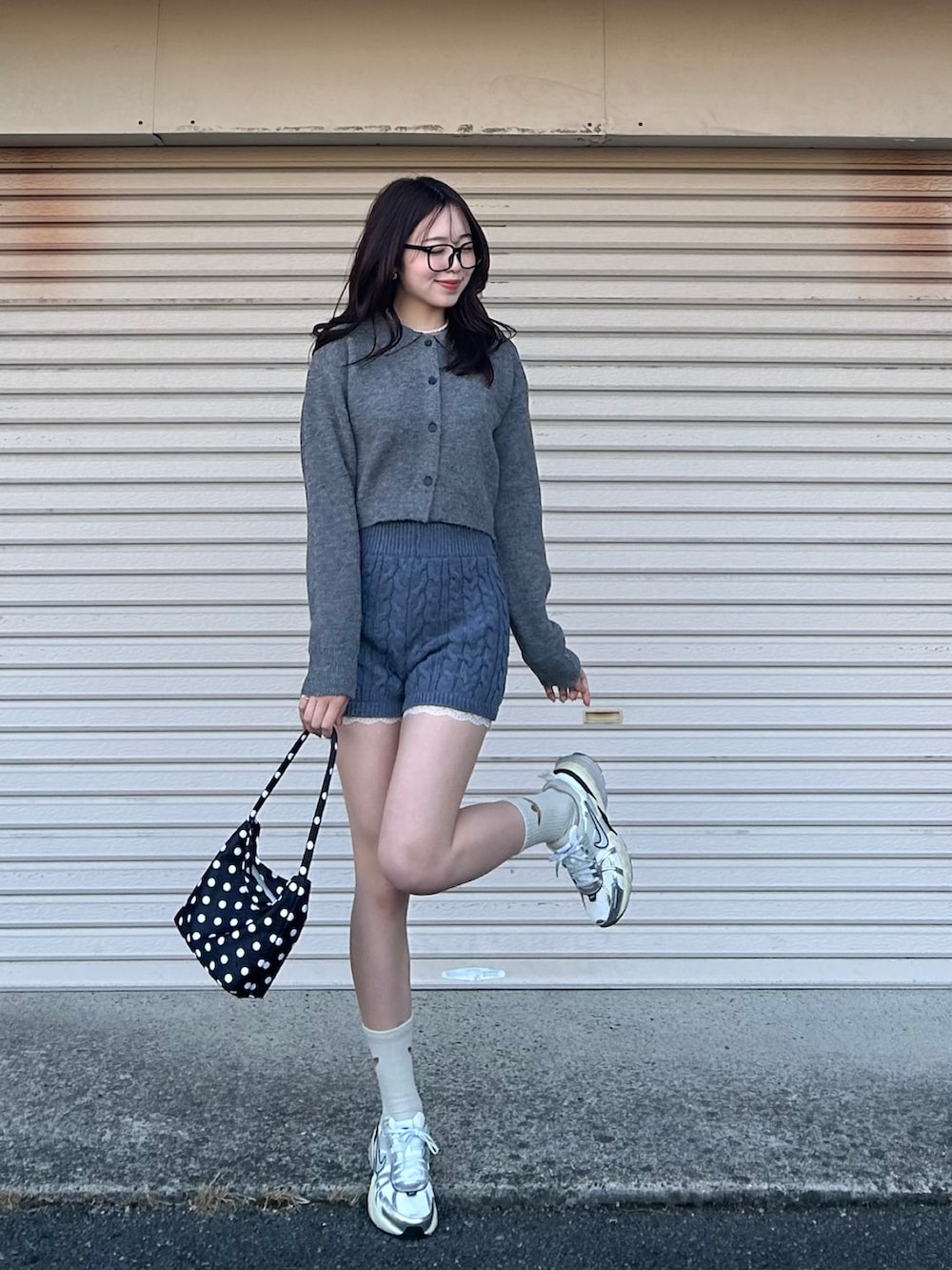 ブラック系のショルダーバッグ、ホワイト系のスニーカー、グレー系のニット/セーターを着用したレディースの冬コーディネートの2枚目の写真