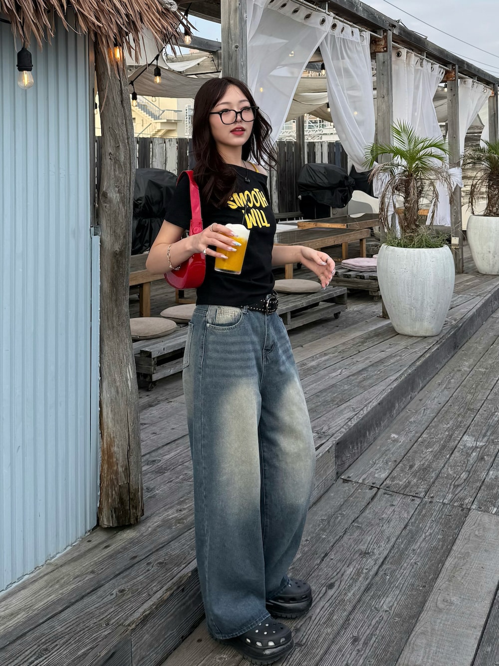 ブラック系のTシャツ/カットソー、ブルー系のデニムパンツ、レッド系のハンドバッグを着用したレディースの夏コーディネートの2枚目の写真