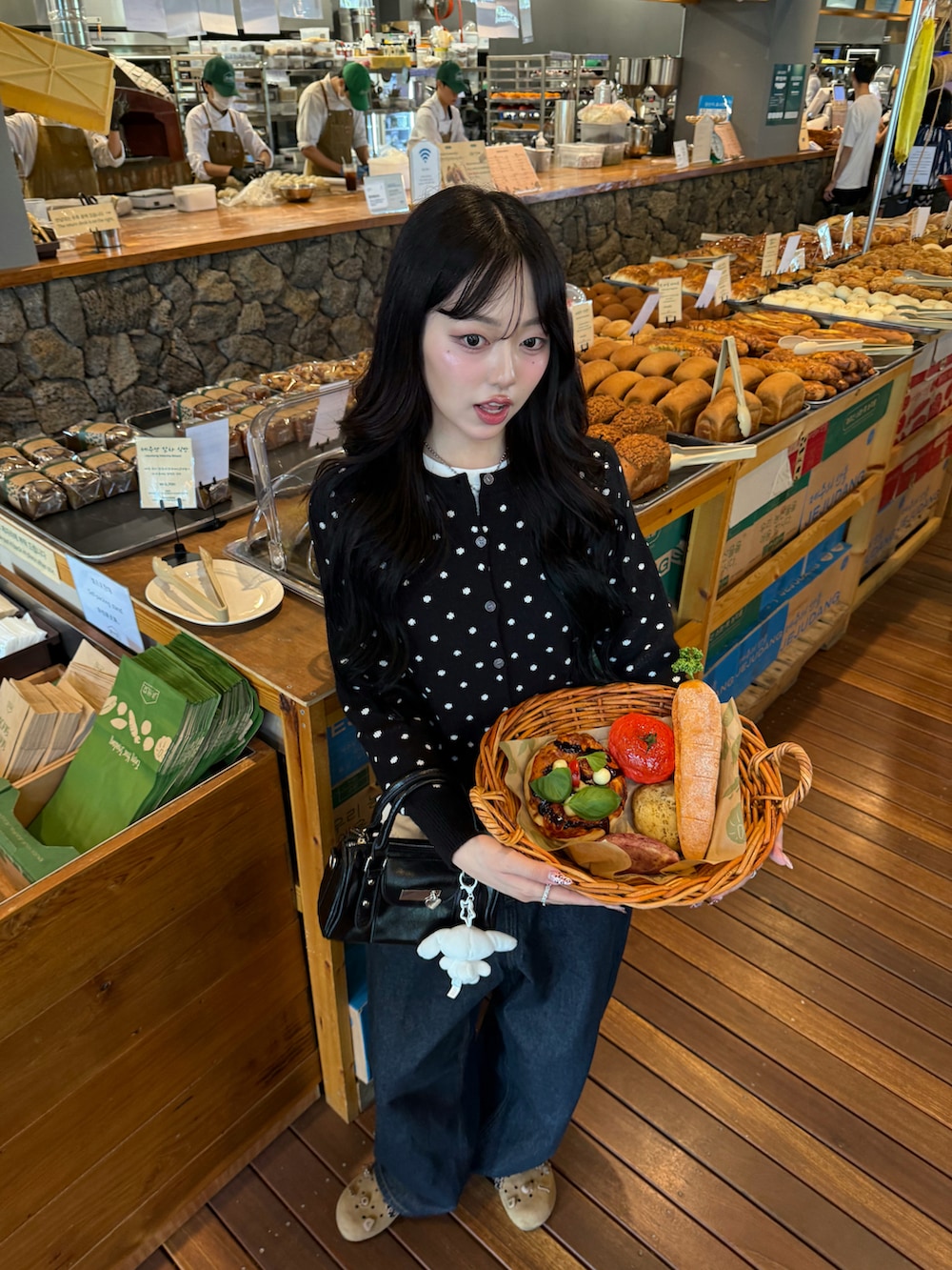 ブラック系のカーディガン/ボレロ、ブラック系のハンドバッグ、ブルー系のデニムパンツを着用したレディースの秋コーディネートの3枚目の写真