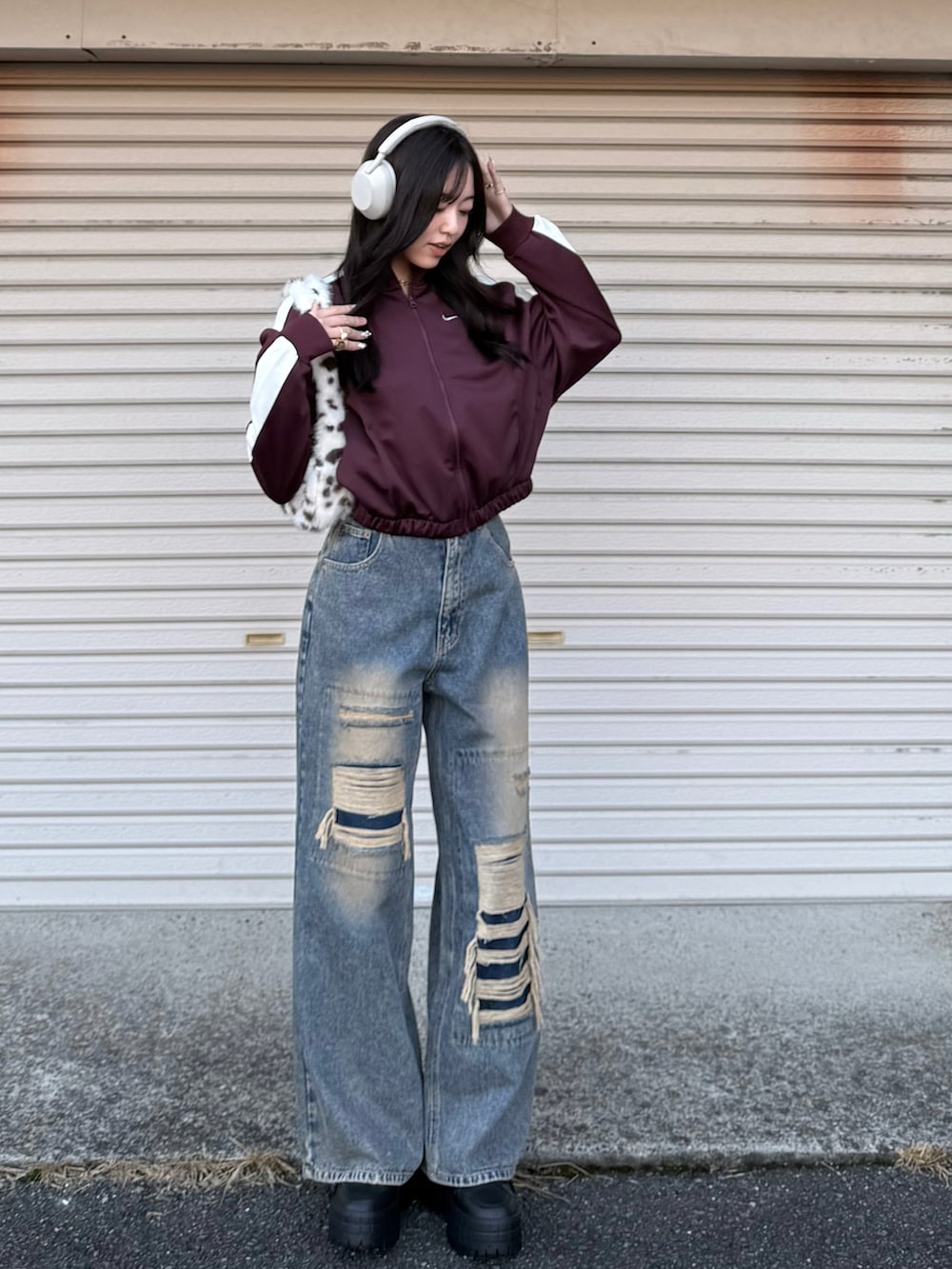 レッド系のブルゾン、ブルー系のデニムパンツ、ブラウン系のハンドバッグを着用したレディースの冬コーディネートの2枚目の写真