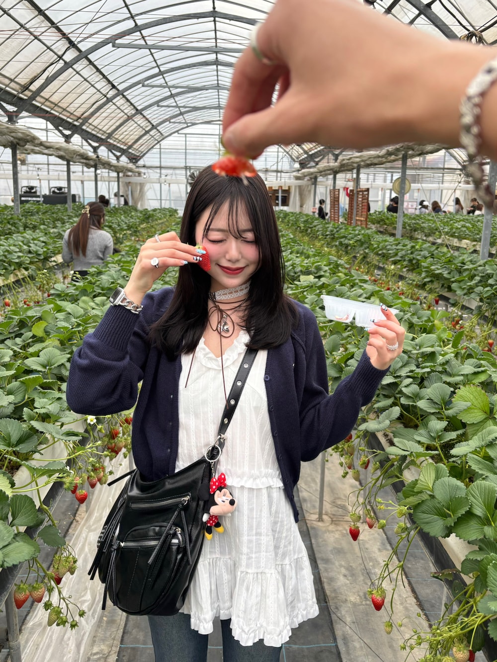 ホワイト系のキャミソール、ブルー系のカーディガン/ボレロ、ブルー系のデニムパンツを着用したレディースの春コーディネートの2枚目の写真