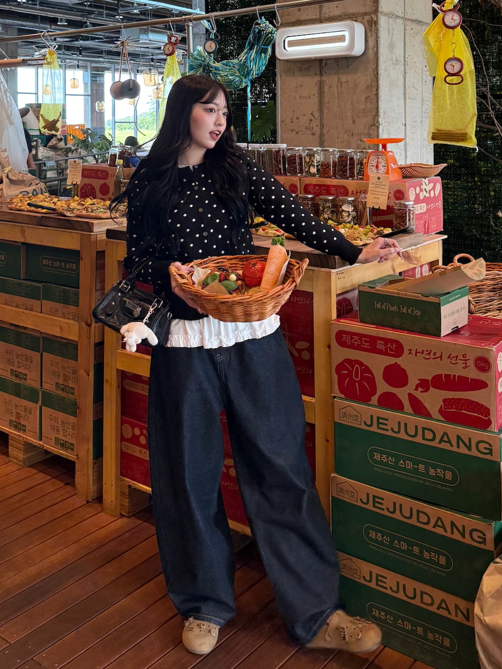 ブラック系のカーディガン/ボレロ、ブラック系のハンドバッグ、ブルー系のデニムパンツを着用したレディースの秋コーディネートの2枚目の写真