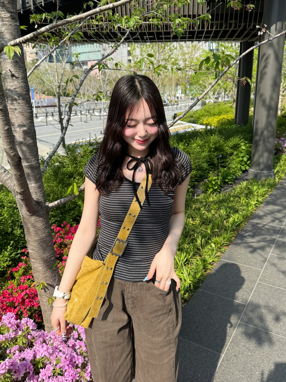 イエロー系のショルダーバッグ、ホワイト系のスニーカー、ブラウン系のデニムパンツを着用したレディースの春コーディネートの2枚目の写真