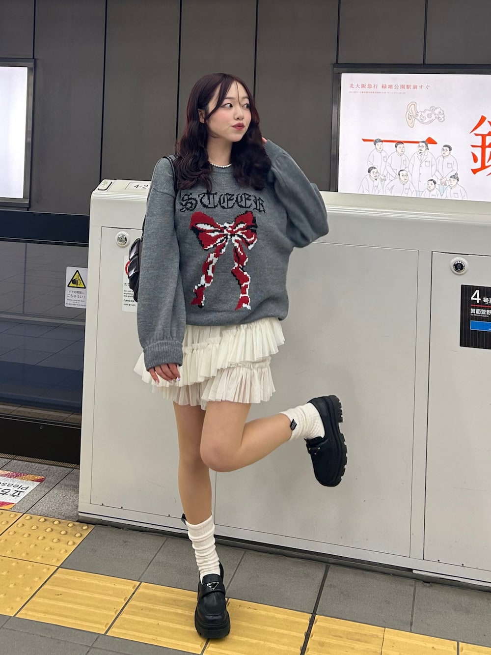 グレー系のニット/セーター、ホワイト系のスカート、ブラウン系のハンドバッグを着用したレディースの冬コーディネートの2枚目の写真