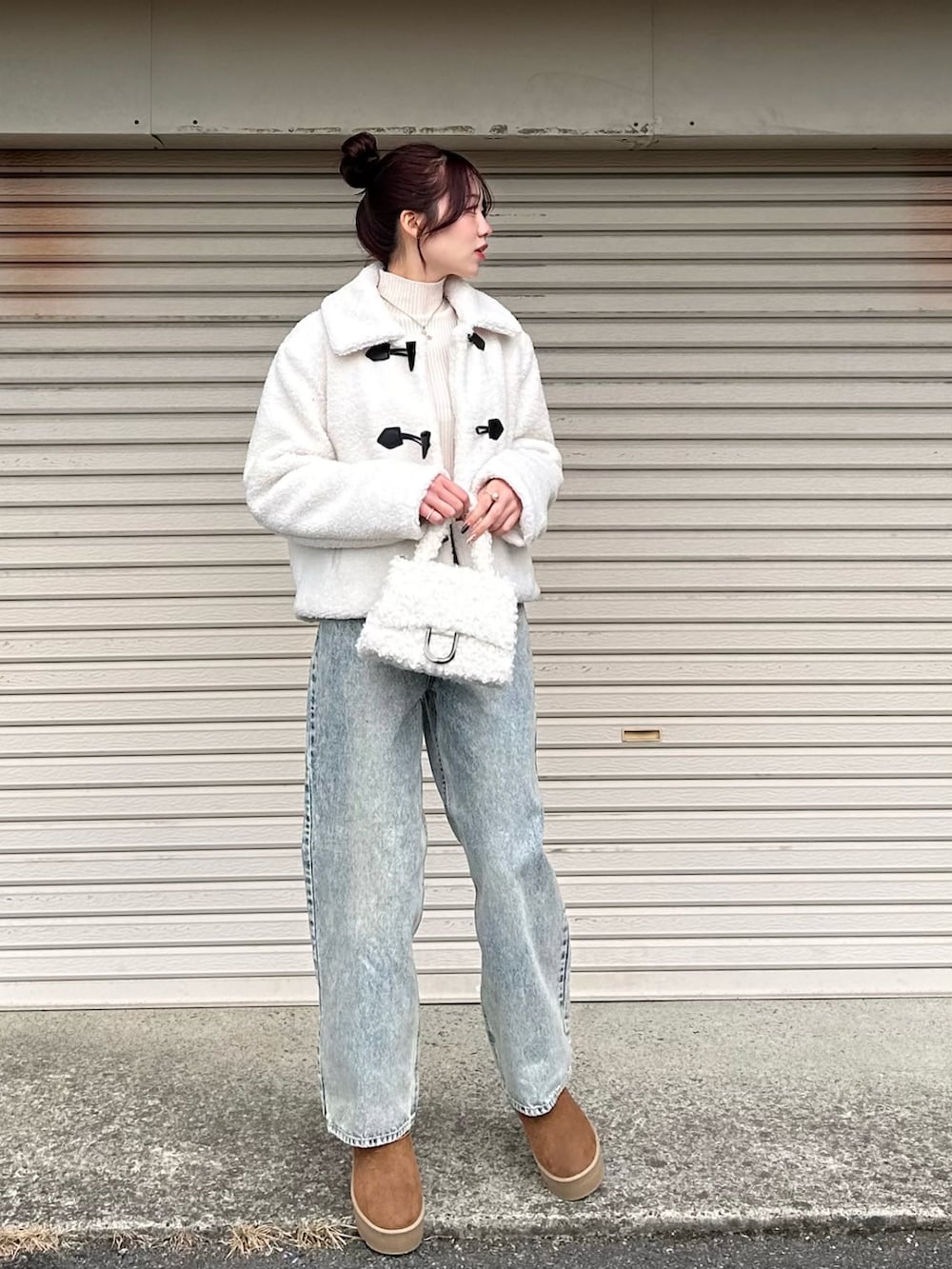 ホワイト系のダッフルコート、ホワイト系のハンドバッグ、ブラウン系のブーツを着用したレディースの冬コーディネートの2枚目の写真