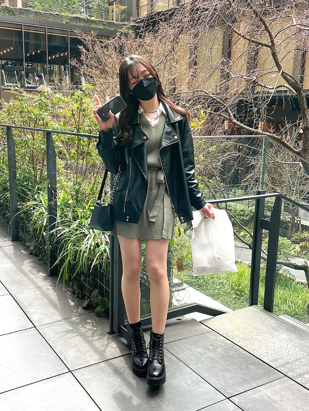 グリーン系のワンピース、ブラック系のライダースジャケット、ブラック系のその他シューズを着用したレディースの春コーディネートの2枚目の写真