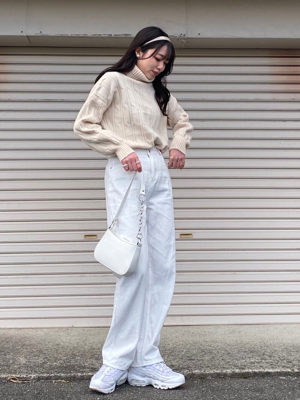 ホワイト系のスニーカー、ホワイト系のニット/セーター、ホワイト系のショルダーバッグを着用したレディースの冬コーディネートの2枚目の写真