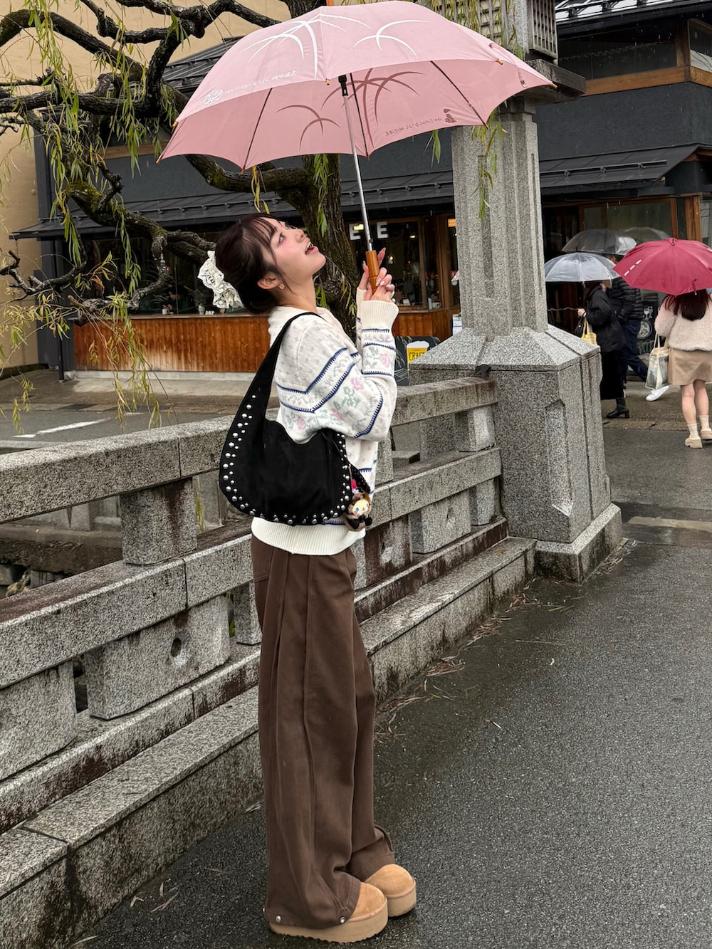 ブラウン系のブーツ、ホワイト系のニット/セーター、ブラウン系のデニムパンツを着用したレディースの冬コーディネートの2枚目の写真