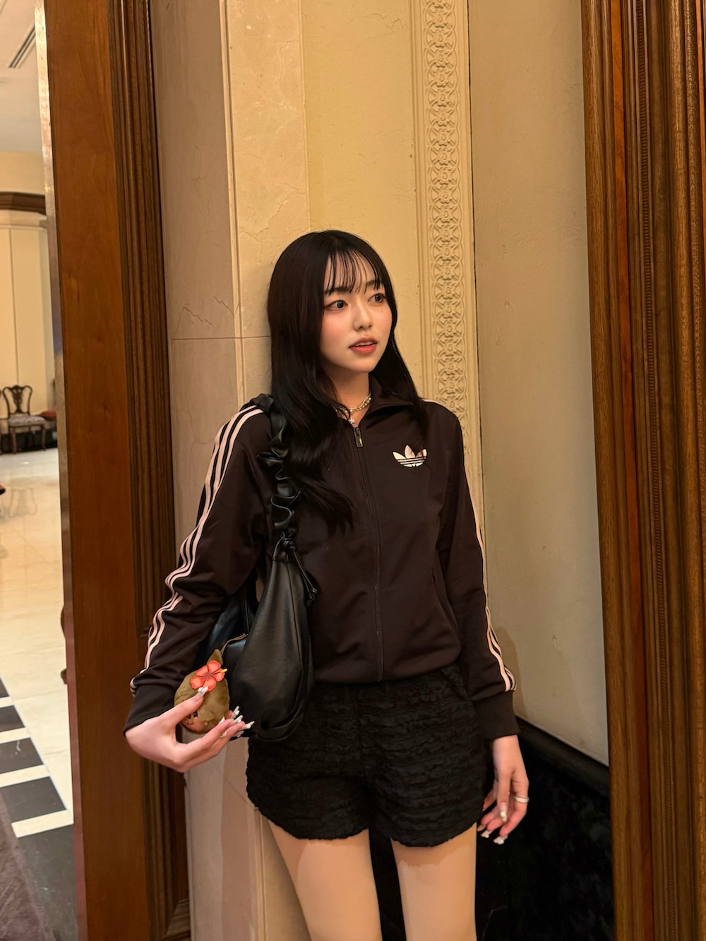 ブラウン系のジャージ、ブラック系のパンツ、ブラック系のサンダルを着用したレディースの春コーディネートの2枚目の写真