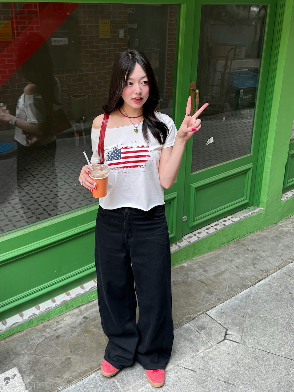 レッド系のスニーカー、レッド系のハンドバッグ、ホワイト系のTシャツ/カットソーを着用したレディースの夏コーディネートの2枚目の写真