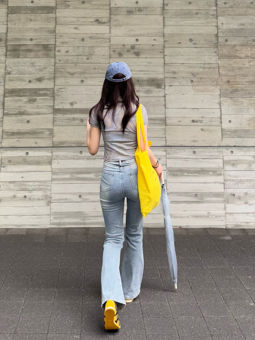 イエロー系のトートバッグ、イエロー系のスリッポン、ブルー系のデニムパンツを着用したレディースの夏コーディネートの2枚目の写真