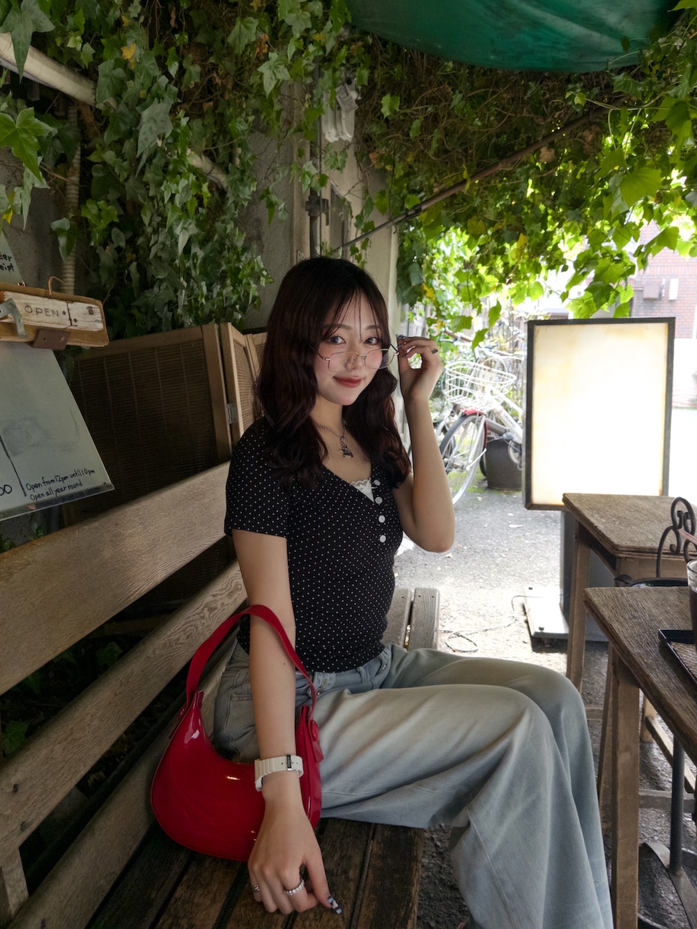 レッド系のハンドバッグ、レッド系のスニーカー、ブルー系のデニムパンツを着用したレディースの春コーディネートの3枚目の写真