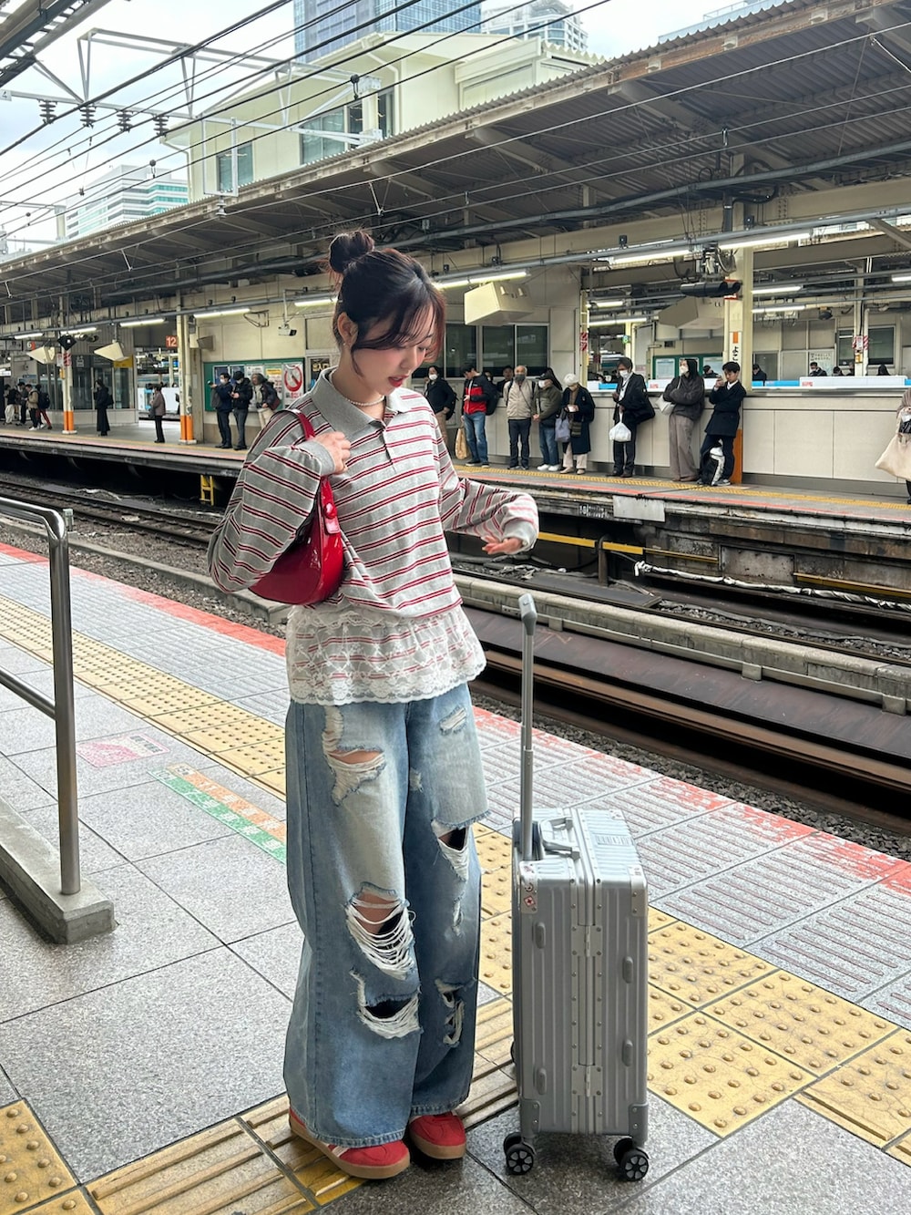 グレー系のニット/セーター、ブルー系のデニムパンツ、レッド系のハンドバッグを着用したレディースの春コーディネートの2枚目の写真