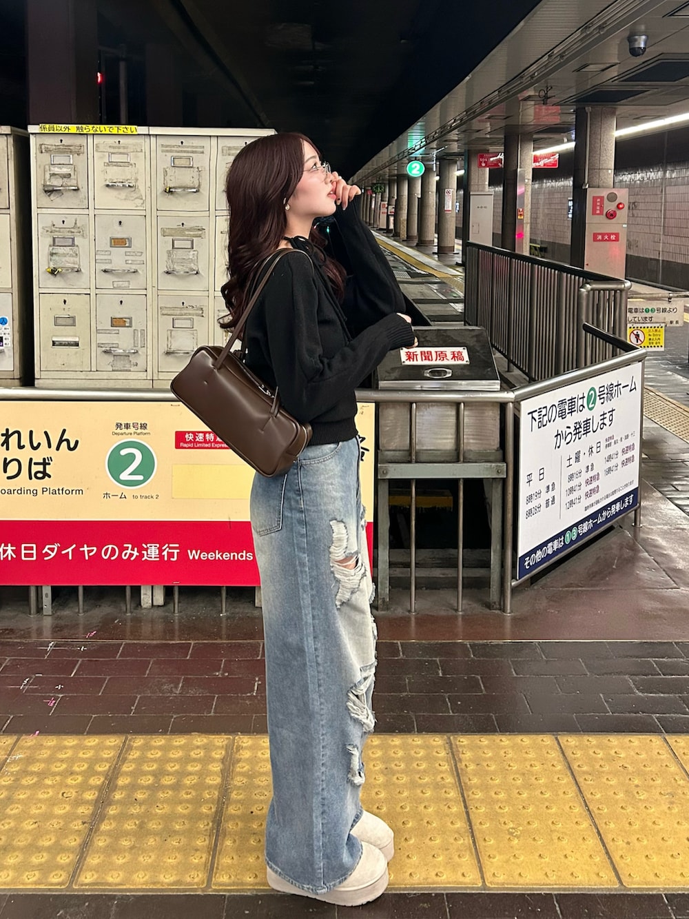 ブラウン系のバッグ、ブルー系のデニムパンツ、ブラウン系のブーツを着用したレディースの冬コーディネートの2枚目の写真