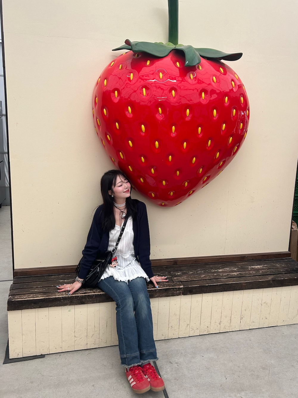 ホワイト系のキャミソール、ブルー系のカーディガン/ボレロ、ブルー系のデニムパンツを着用したレディースの春コーディネートの4枚目の写真