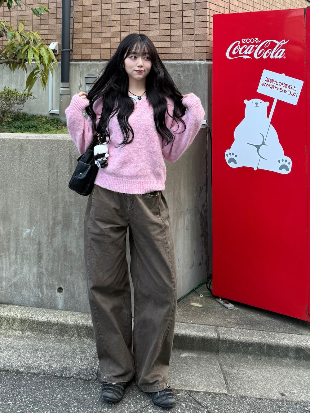 ピンク系のニット/セーター、ブラウン系のデニムパンツ、ブラック系のスニーカーを着用したレディースの秋コーディネートの2枚目の写真