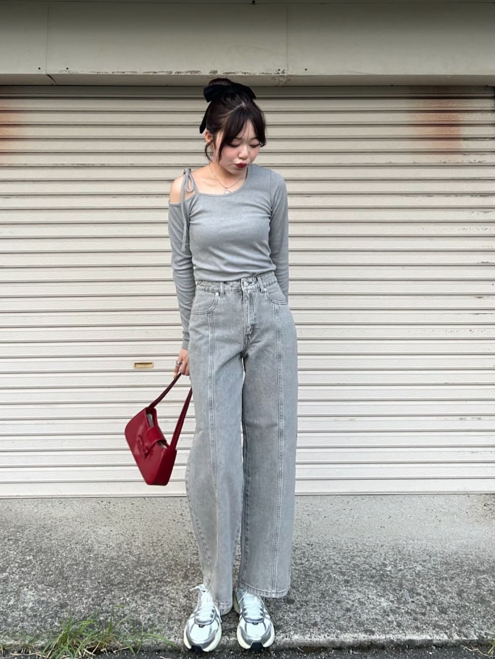 レッド系のハンドバッグ、グレー系のニット/セーター、ホワイト系のスニーカーを着用したレディースの冬コーディネートの2枚目の写真