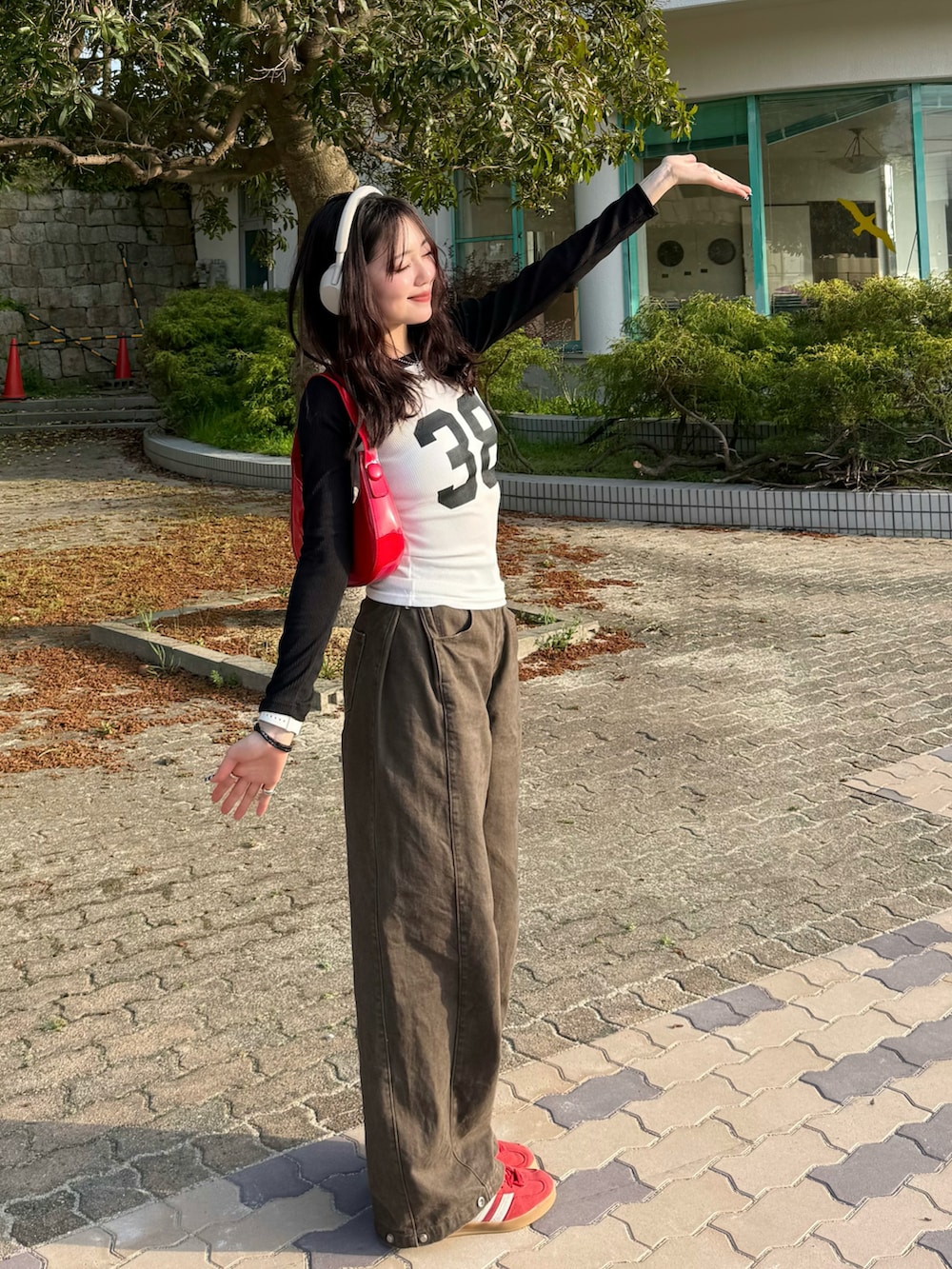 ホワイト系のTシャツ/カットソー、ブラウン系のデニムパンツ、レッド系のハンドバッグを着用したレディースの春コーディネートの2枚目の写真