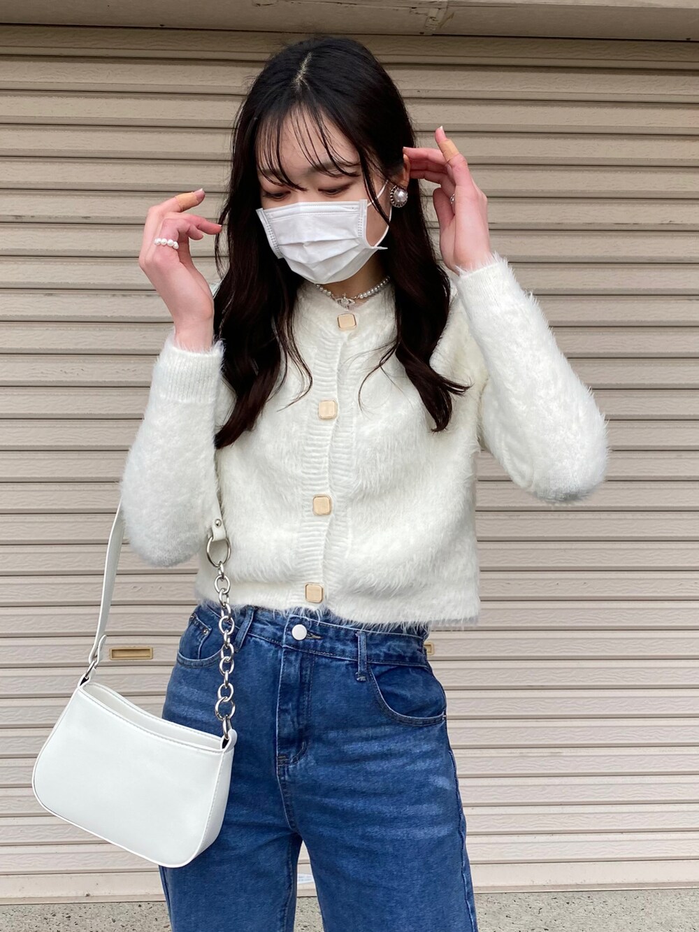 ブルー系のデニムパンツ、ホワイト系のカーディガン/ボレロ、ホワイト系のショルダーバッグを着用したレディースの冬コーディネートの3枚目の写真