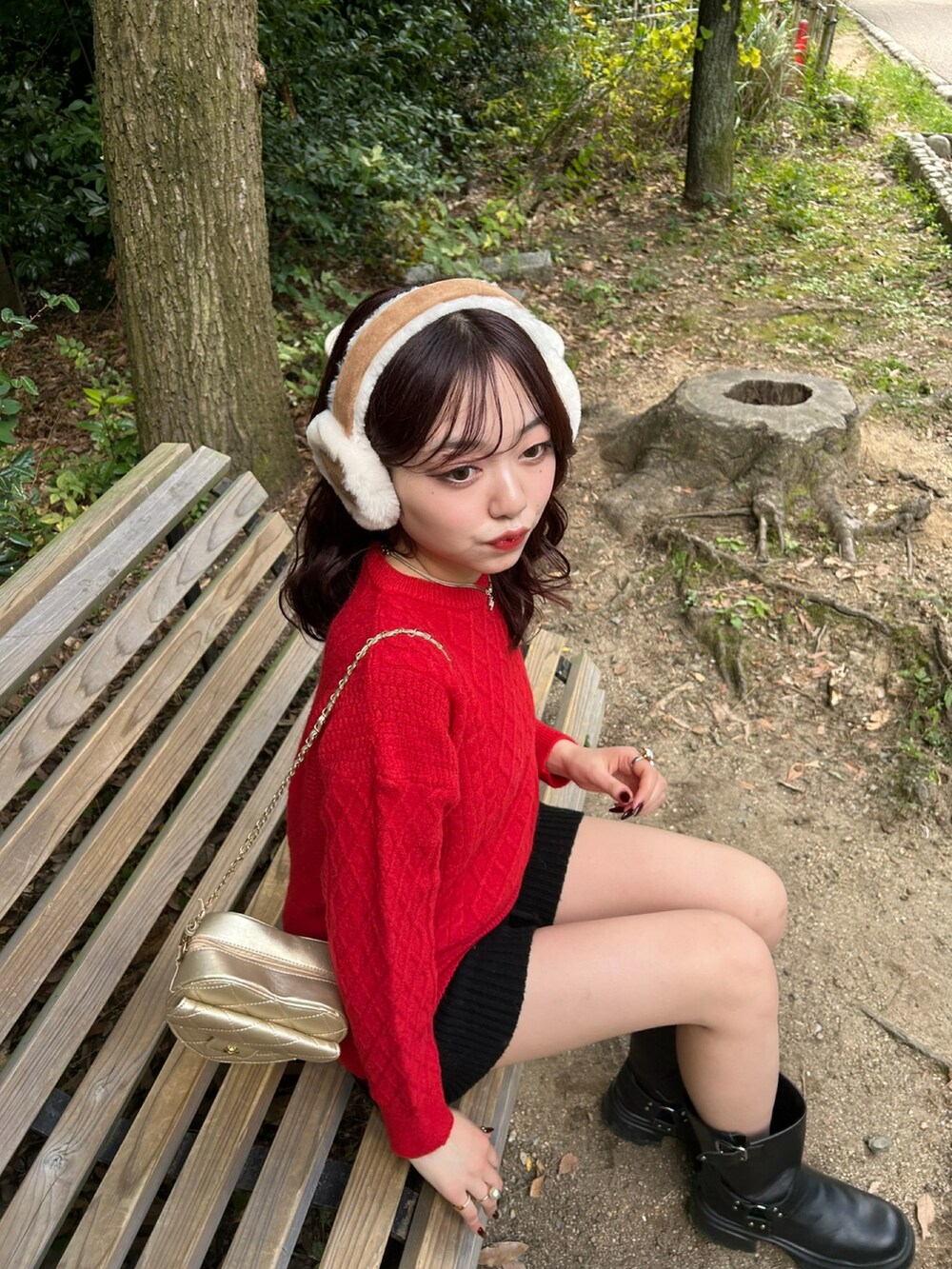 レッド系のニット/セーター、ゴールド系のショルダーバッグ、ブラック系のブーツを着用したレディースの冬コーディネートの2枚目の写真