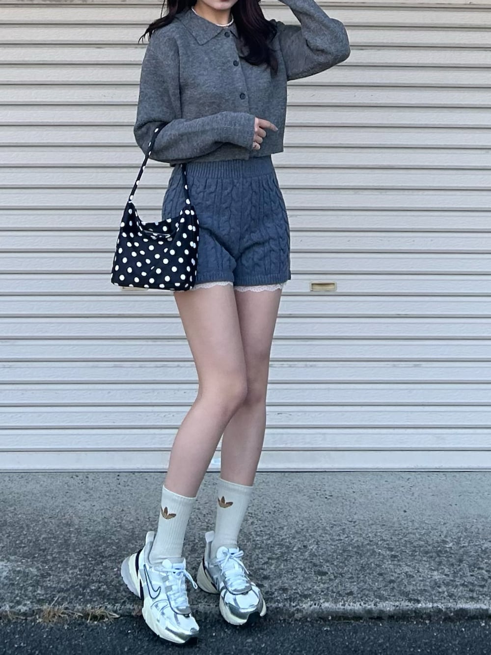 ブラック系のショルダーバッグ、ホワイト系のスニーカー、グレー系のニット/セーターを着用したレディースの冬コーディネートの4枚目の写真