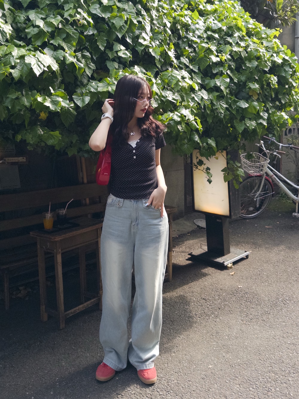 レッド系のハンドバッグ、レッド系のスニーカー、ブルー系のデニムパンツを着用したレディースの春コーディネートの2枚目の写真