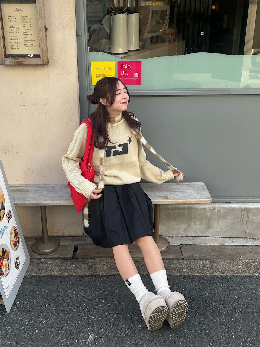 ベージュ系のニット/セーター、ブラック系のスカート、レッド系のショルダーバッグを着用したレディースの冬コーディネートの2枚目の写真