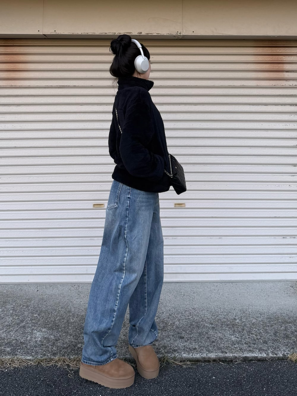 ブラウン系のブーツ、ブルー系のデニムパンツ、ブラック系のショルダーバッグを着用したレディースの秋コーディネートの2枚目の写真