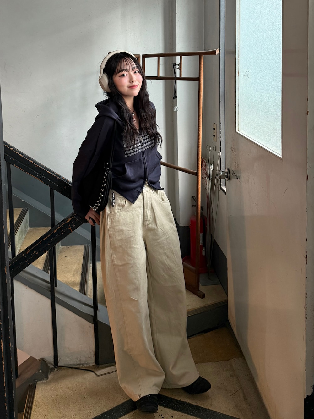 ベージュ系のデニムパンツ、ブルー系のパーカー、ブラック系のスニーカーを着用したレディースの冬コーディネートの2枚目の写真