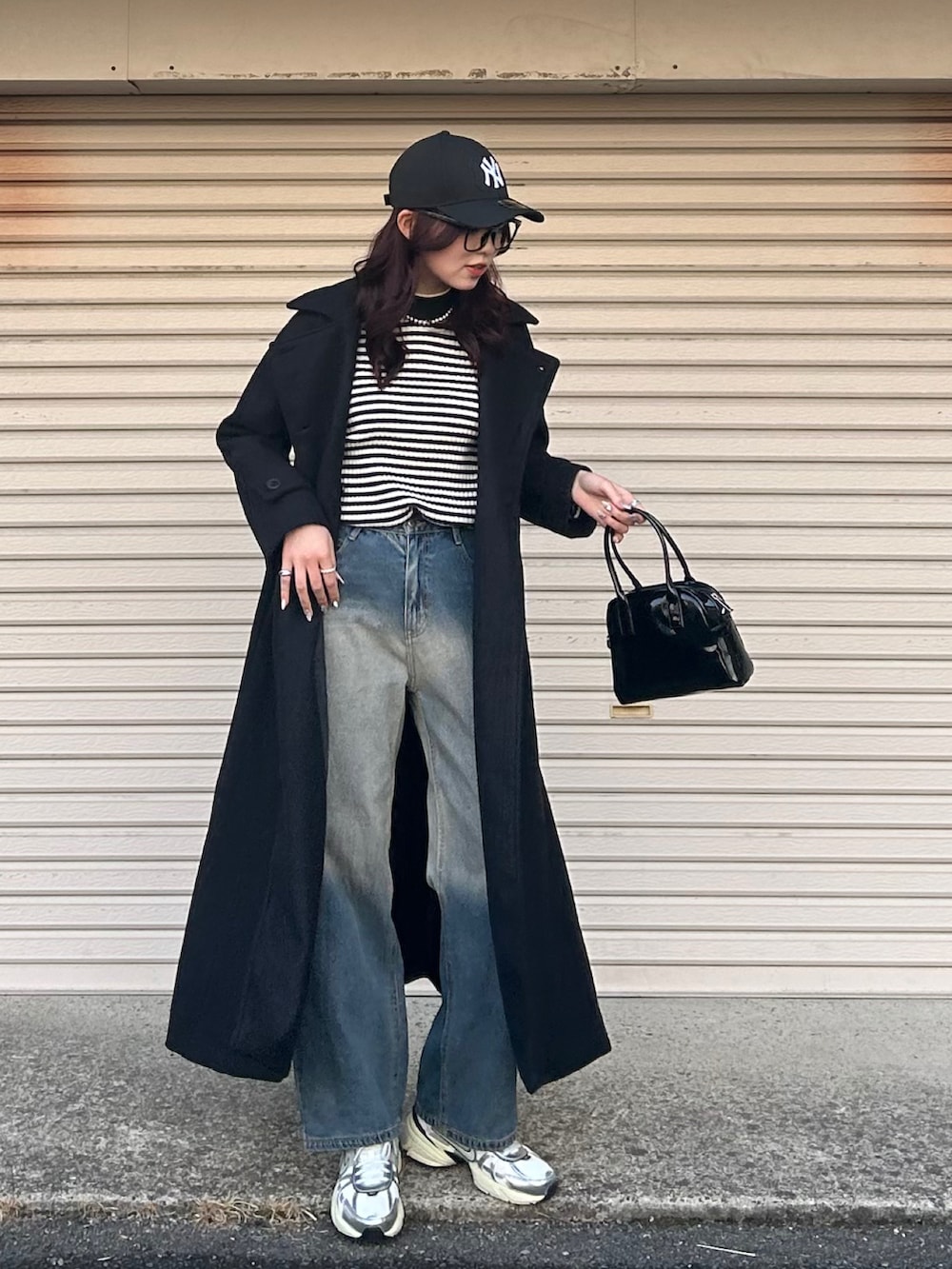 ブラック系のニット/セーター、ブルー系のデニムパンツ、ブラック系のボストンバッグを着用したレディースの冬コーディネートの2枚目の写真