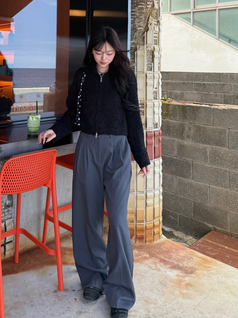 ブラック系のニット/セーター、ブラック系のショルダーバッグ、グレー系のスラックスを着用したレディースの秋コーディネートの2枚目の写真