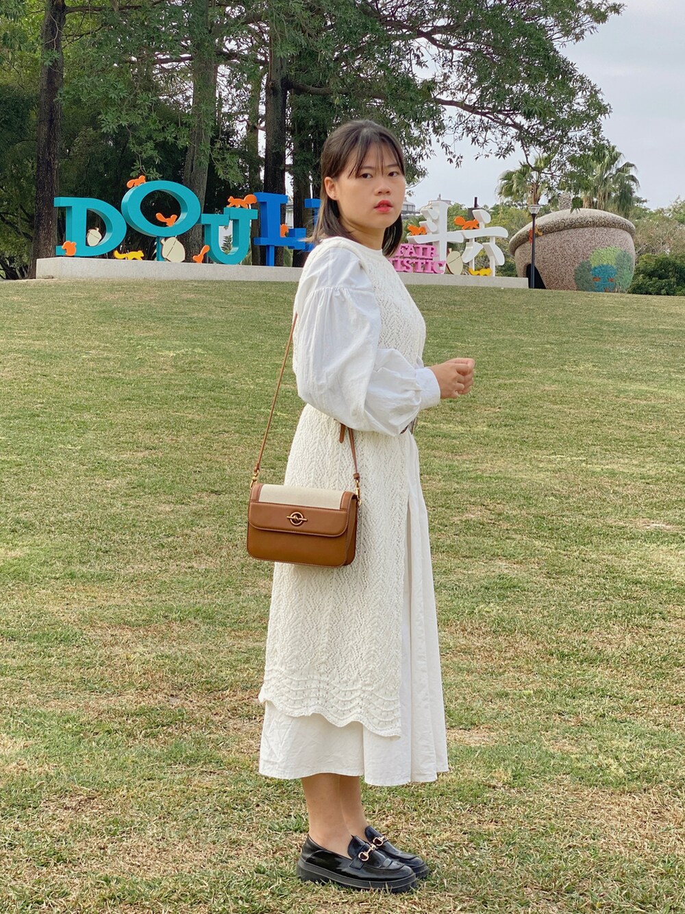 ブラウン系のショルダーバッグ、ブラック系のローファーを着用したレディースの冬コーディネートの2枚目の写真