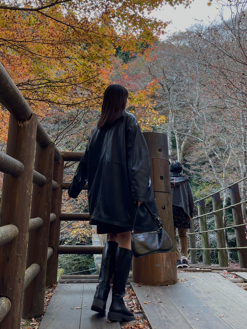ブラック系のテーラードジャケット、ブラック系のショルダーバッグ、ブラック系のブーツを着用したレディースの秋コーディネートの2枚目の写真
