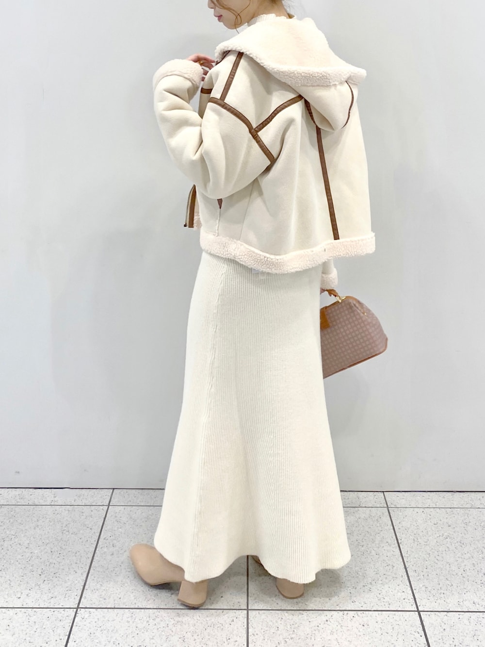 ベージュ系のショルダーバッグ、ベージュ系のブーツ、ホワイト系のワンピースを着用したレディースの秋コーディネートの2枚目の写真