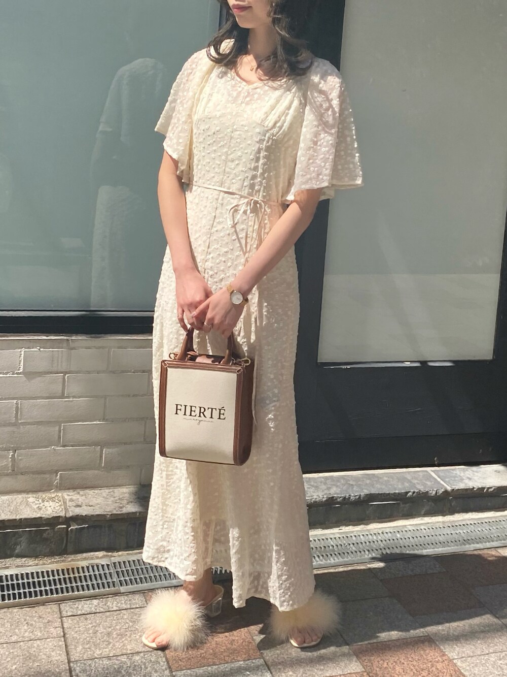 イエロー系のショルダーバッグ、ホワイト系のワンピースを着用したレディースの春コーディネートの2枚目の写真