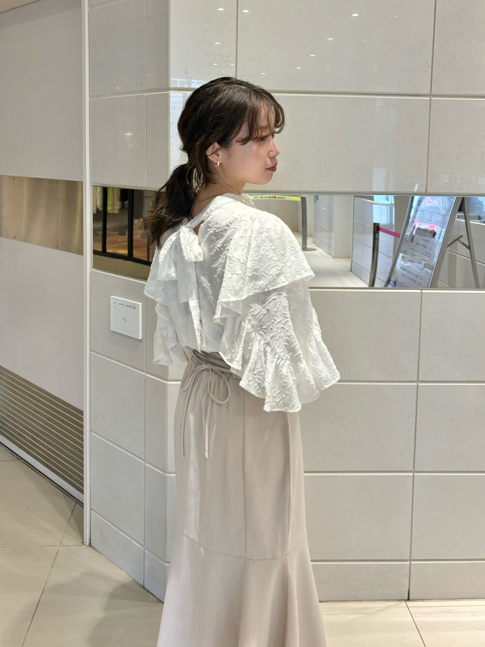 ホワイト系のショルダーバッグ、ホワイト系のシャツ/ブラウス、ベージュ系のスカートを着用したレディースの春コーディネートの4枚目の写真