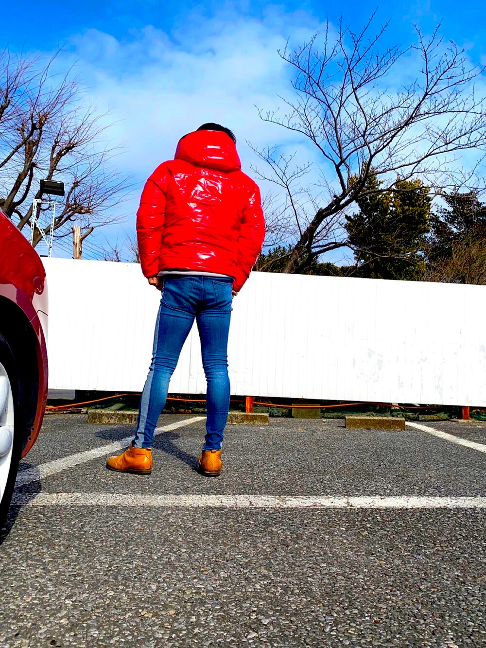 レッド系のダウンジャケット/コート、ブルー系のデニムパンツ、ブラウン系のブーツを着用したメンズの冬コーディネートの2枚目の写真