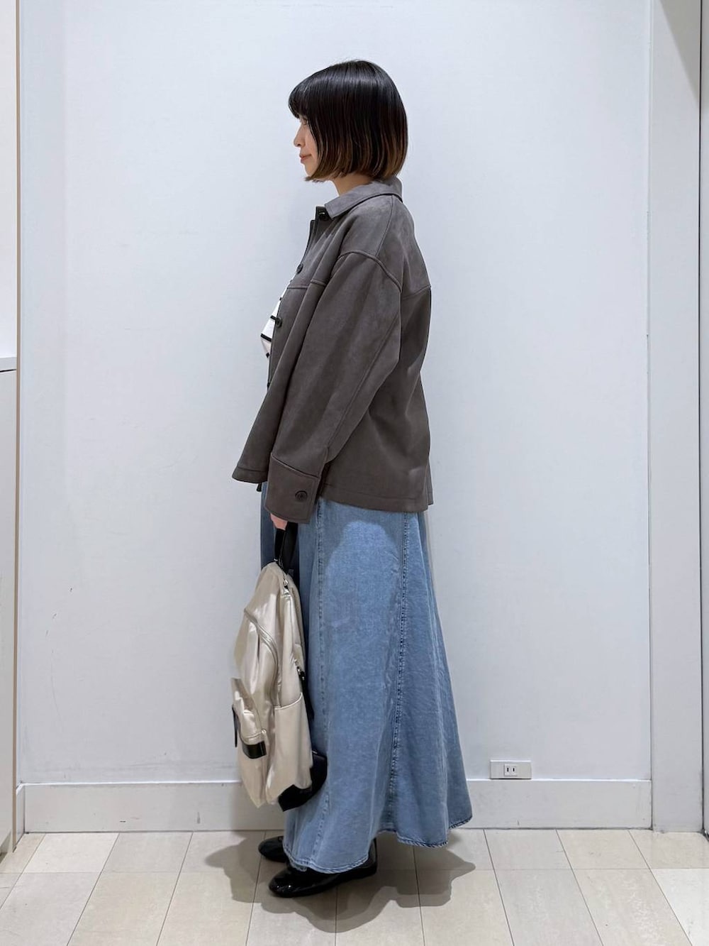 ブラック系のバレエシューズ、ホワイト系のバックパック/リュック、グレー系のテーラードジャケットを着用したレディースの冬コーディネートの2枚目の写真