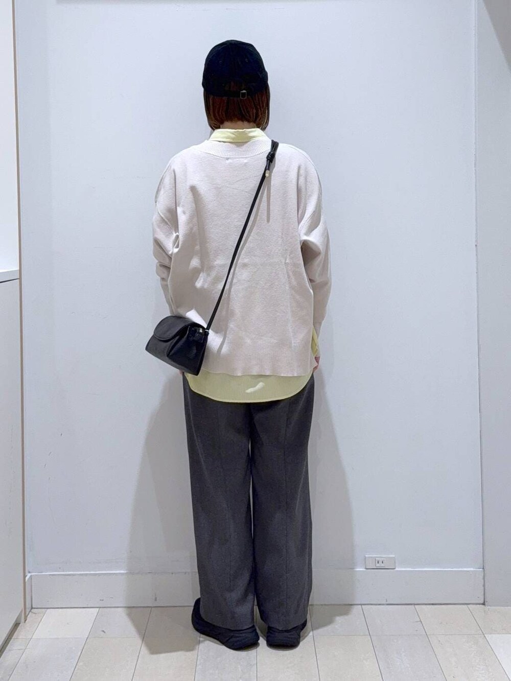 イエロー系のシャツ/ブラウス、ホワイト系のニット/セーター、ブラック系のショルダーバッグを着用したレディースの冬コーディネートの3枚目の写真