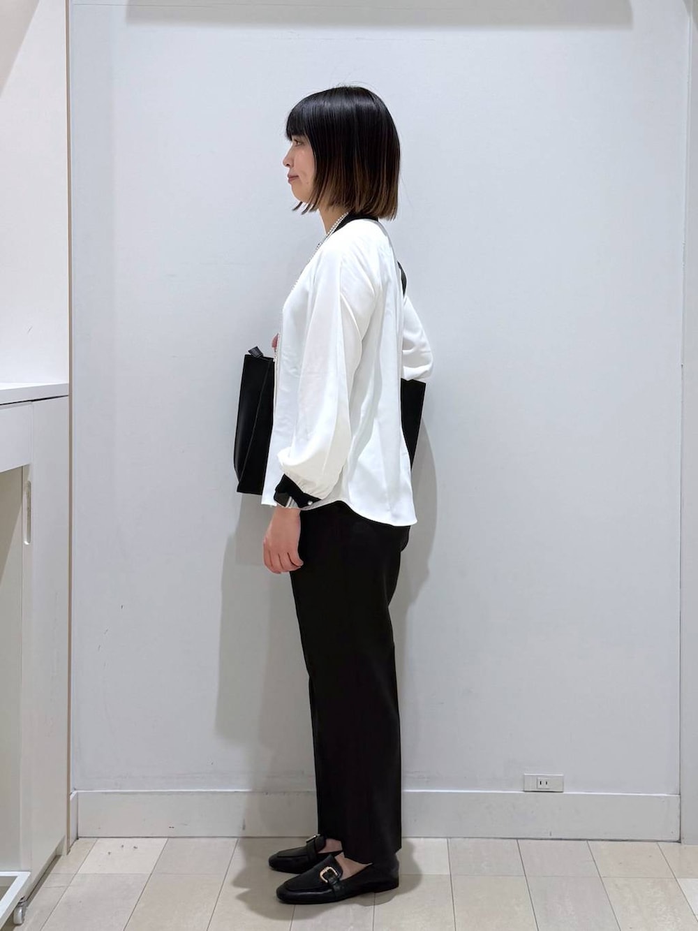ブラック系のローファー、ホワイト系のシャツ/ブラウス、ブラック系のトートバッグを着用したレディースの春コーディネートの2枚目の写真