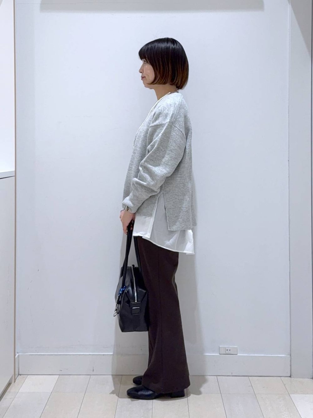 ブラック系のボストンバッグ、シルバー系のニット/セーター、ホワイト系のTシャツ/カットソーを着用したレディースの冬コーディネートの2枚目の写真