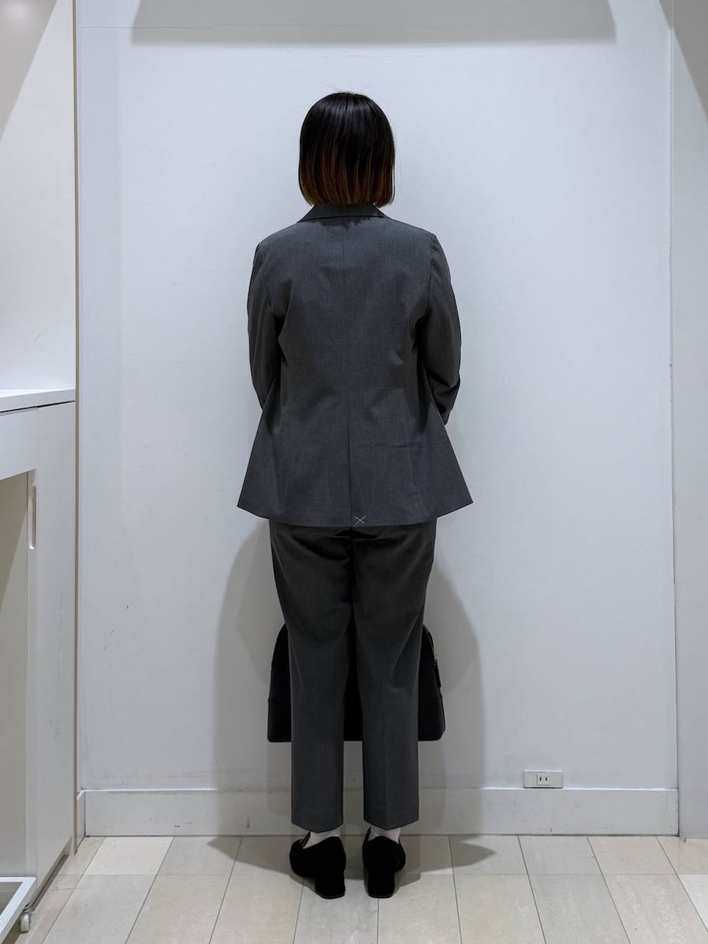 ブラック系のローファー、グレー系のスラックス、ブラック系のボストンバッグを着用したレディースの冬コーディネートの3枚目の写真