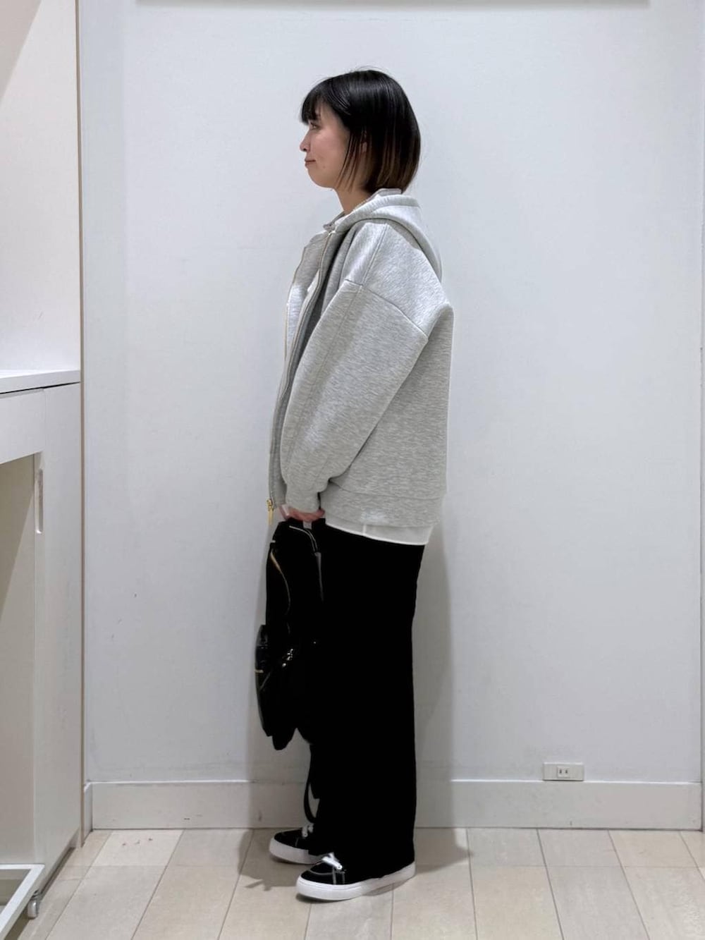 ブラック系のバックパック/リュック、グレー系のパーカー、ホワイト系のタンクトップを着用したレディースの春コーディネートの2枚目の写真