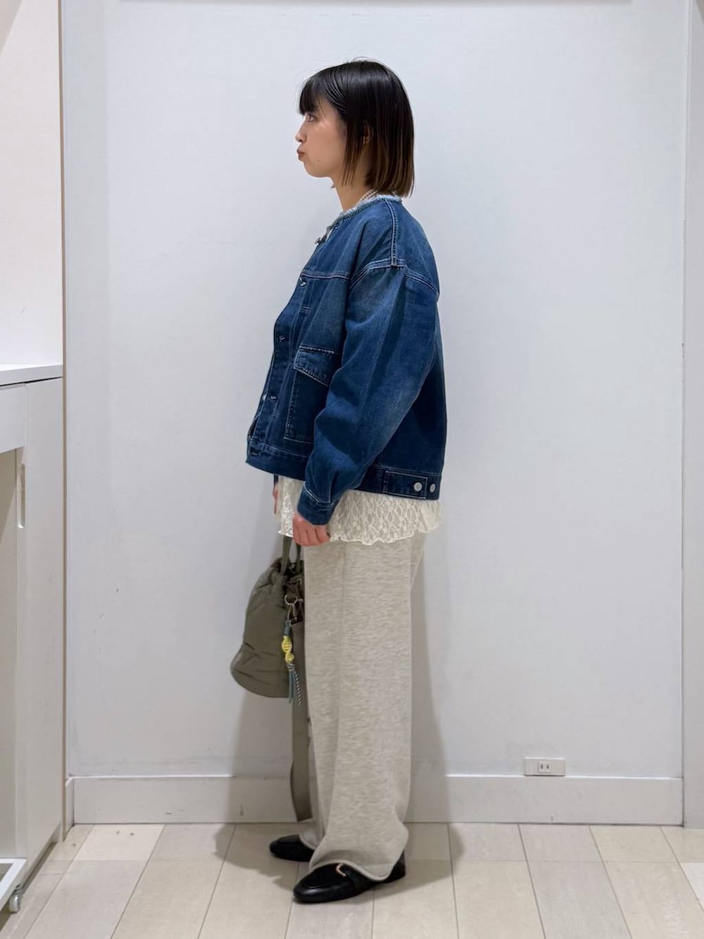 ブラック系のローファー、グリーン系のハンドバッグ、ブルー系のデニムジャケットを着用したレディースの春コーディネートの2枚目の写真