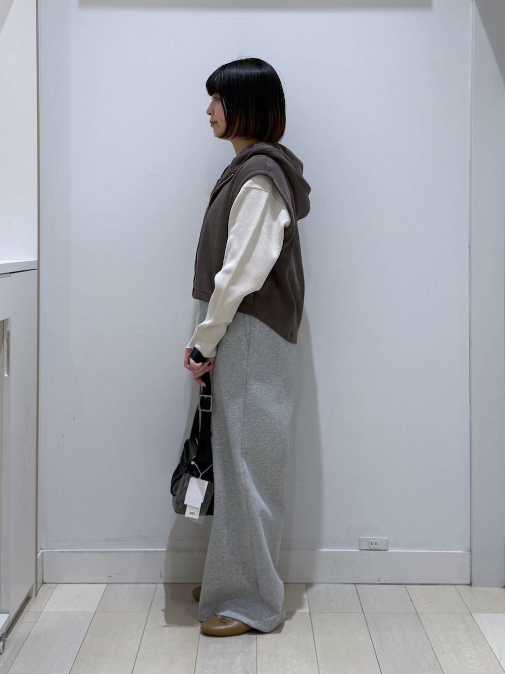 ブラック系のバレエシューズ、ホワイト系のニット/セーター、ブラック系のショルダーバッグを着用したレディースの冬コーディネートの2枚目の写真