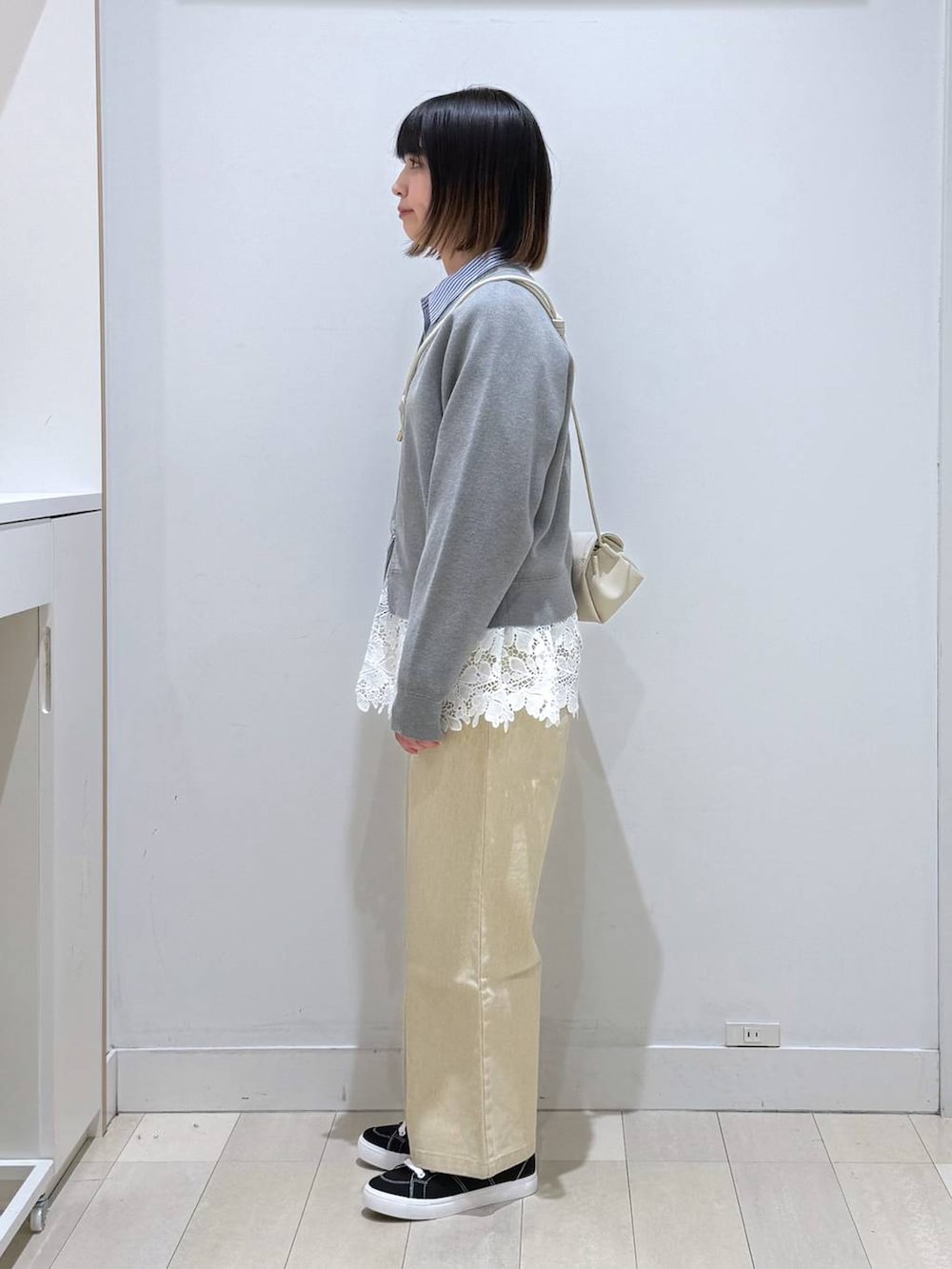 ベージュ系のショルダーバッグ、ベージュ系のデニムパンツ、グレー系のカーディガン/ボレロを着用したレディースの春コーディネートの2枚目の写真